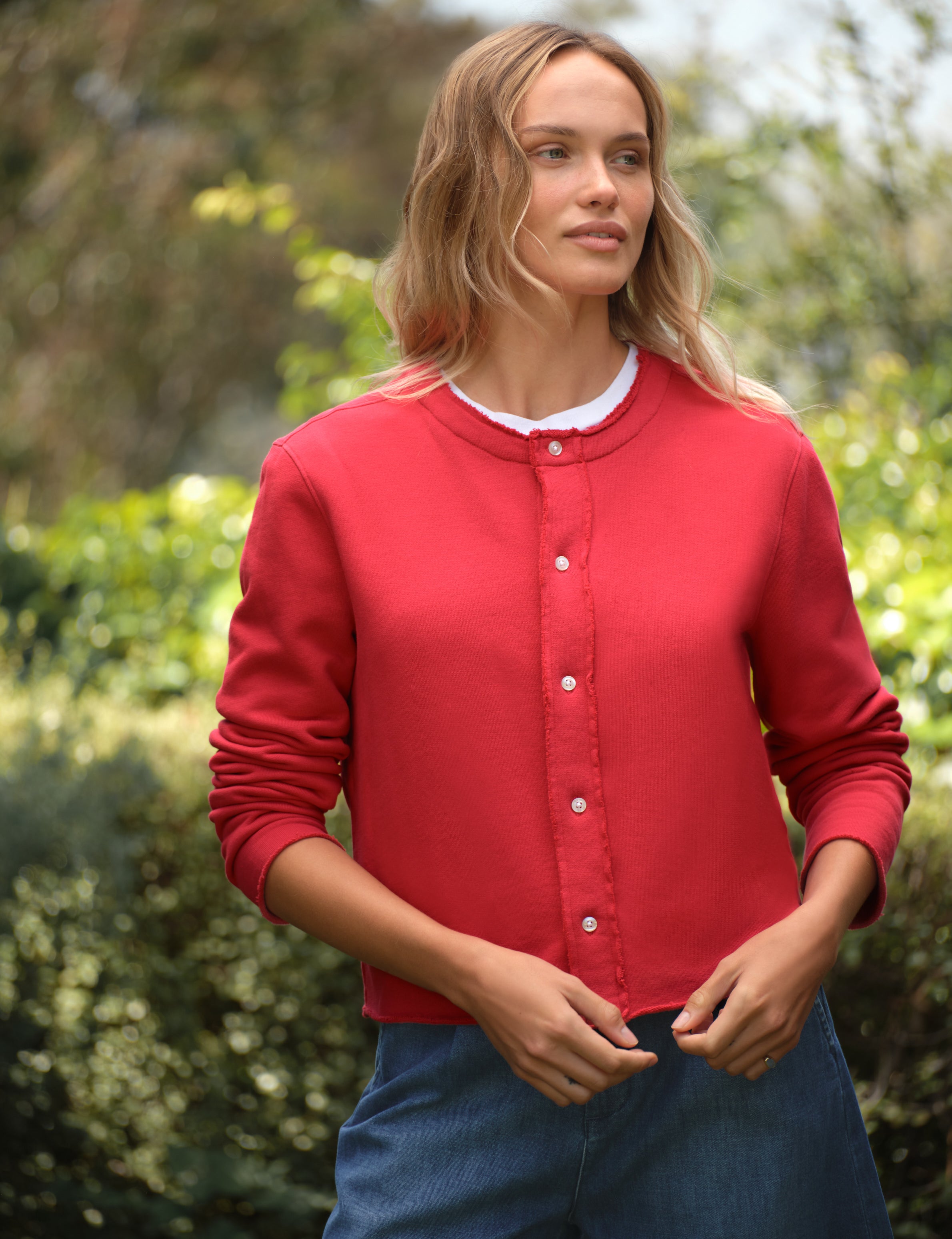 Woman wearing a red cardigan with a blurred green background, front view