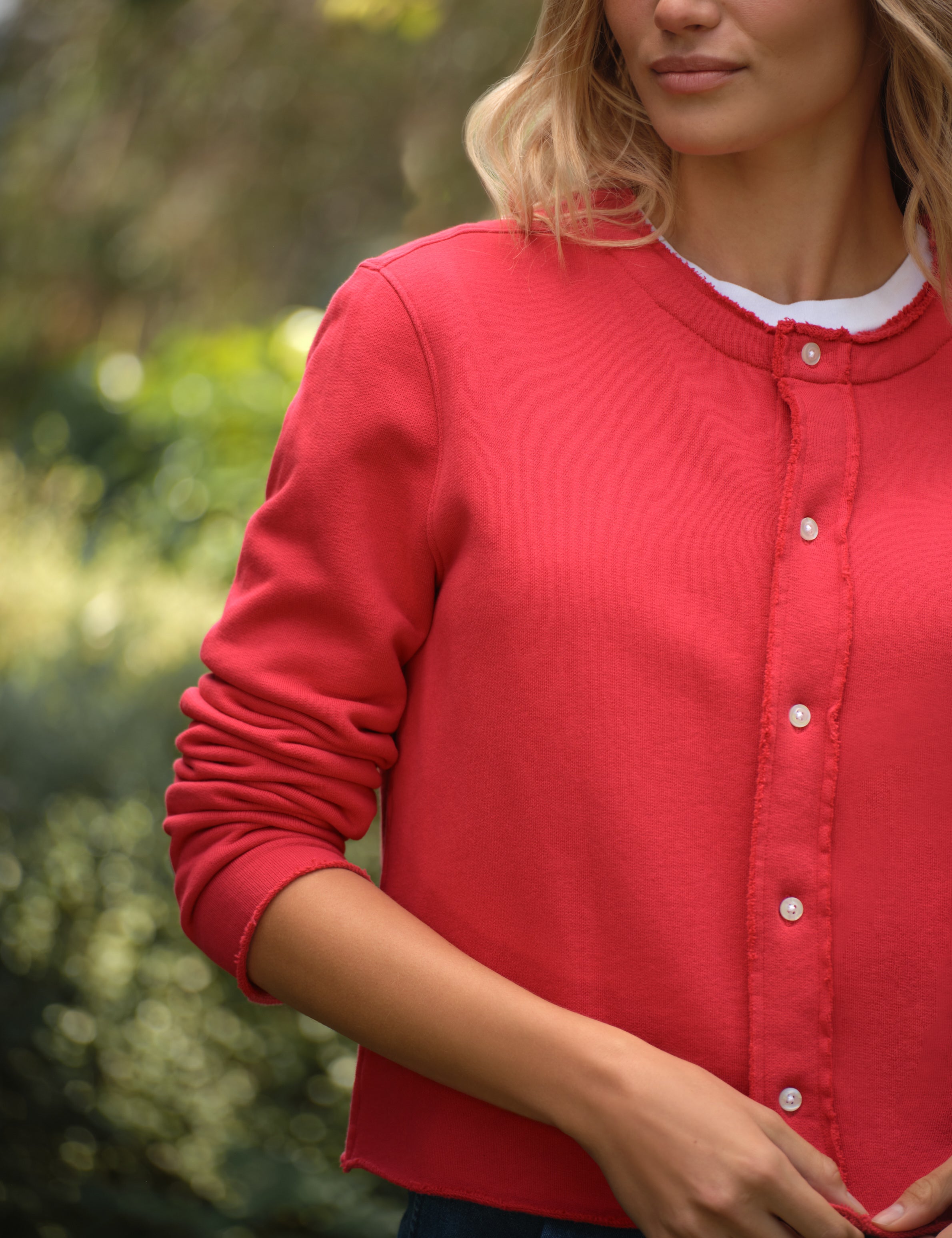 Person wearing a red cardigan with a blurred green background, view 3