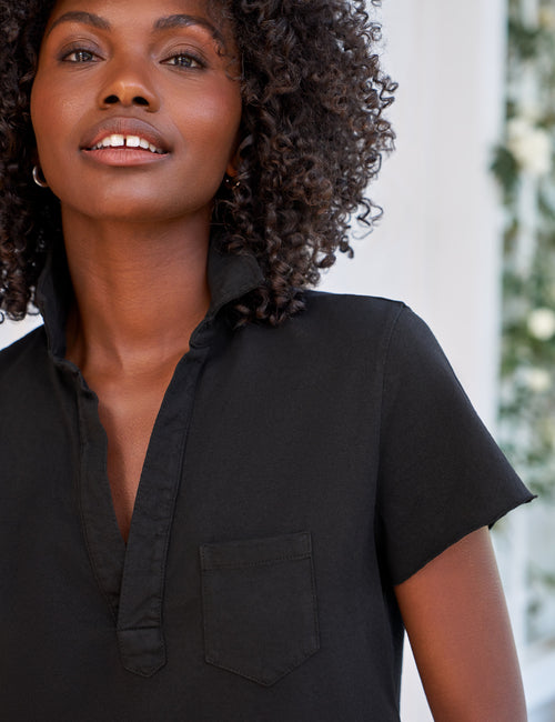 Woman wearing a black short-sleeve shirt with a blurred background, view 3