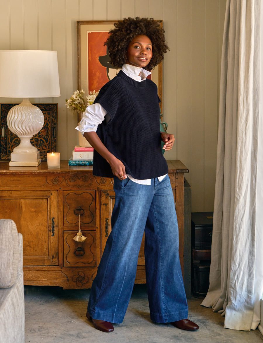 Woman standing in a room with a lamp, cabinet, and decorative items.