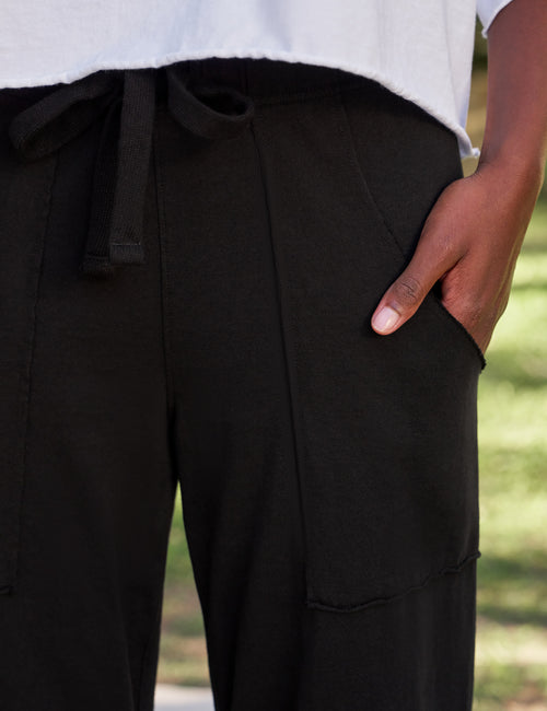 Person wearing black pants with a blurred background, view 3