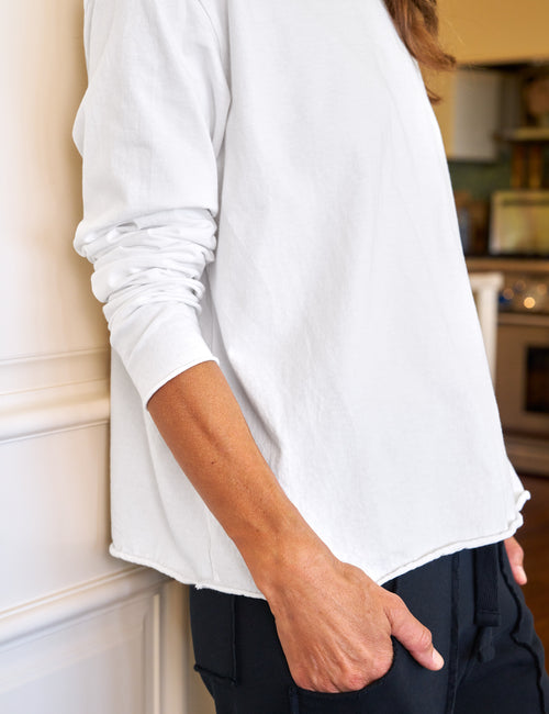 Person wearing a white long-sleeve shirt in an indoor setting, view 5