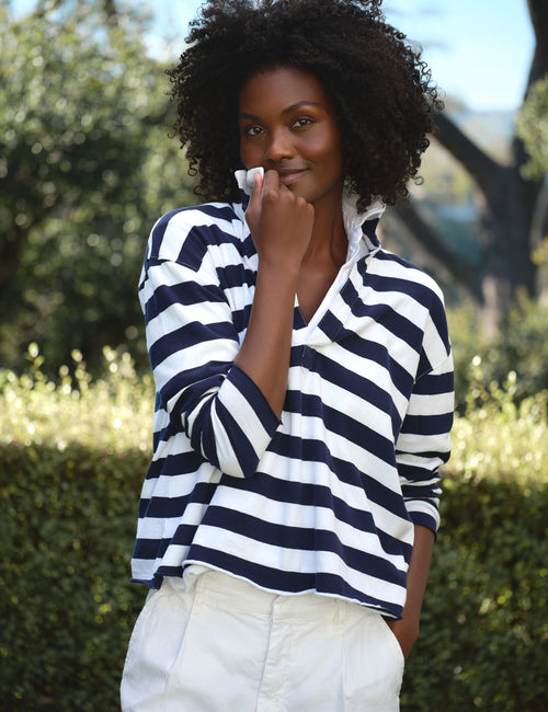 Woman wearing a navy and white striped shirt with a blurred natural background, view 5