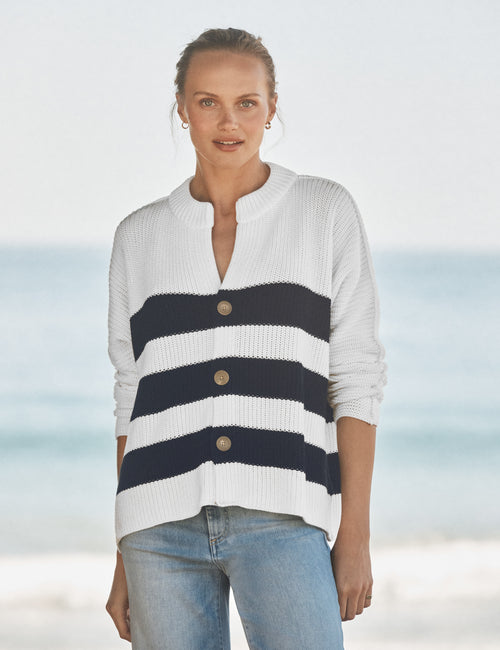 Woman wearing a white and navy striped sweater with a blurred beach background, front view