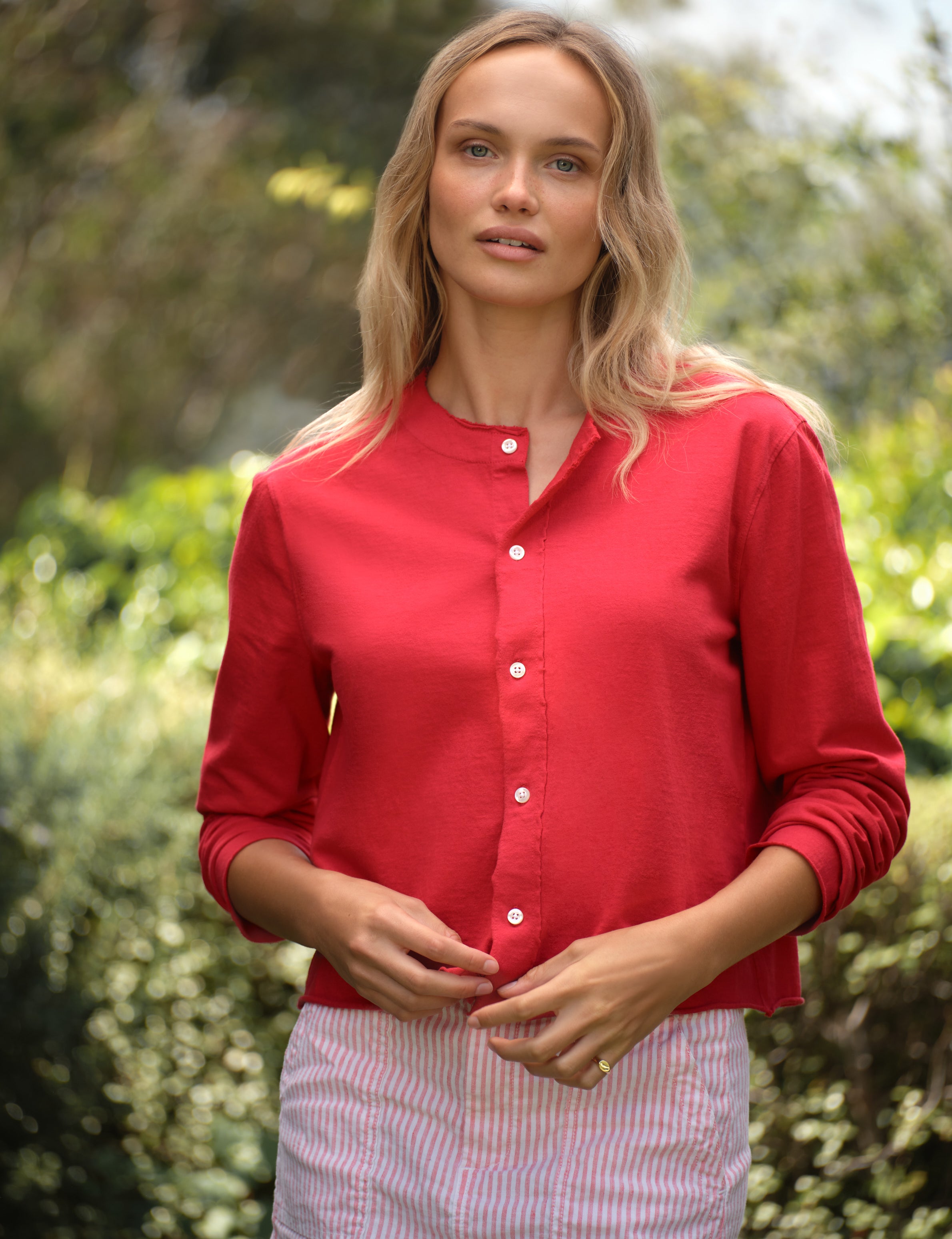 Woman wearing a red shirt with a blurred natural background, view 3