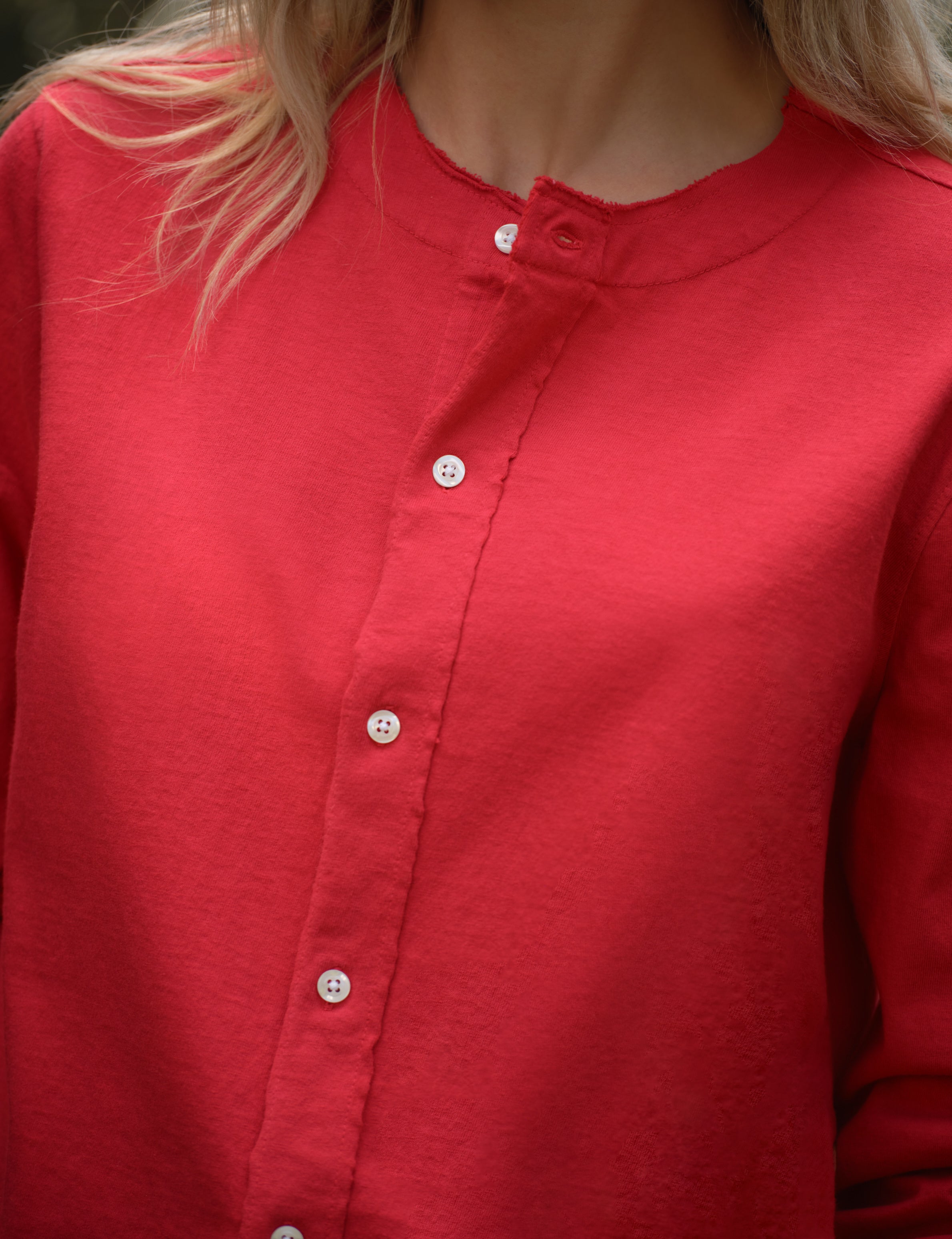 Close-up of a red cardigan worn by a person with blonde hair., view 5