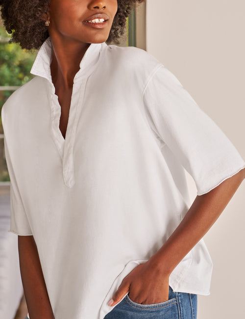 Woman wearing a white oversized shirt with a neutral background, view 3