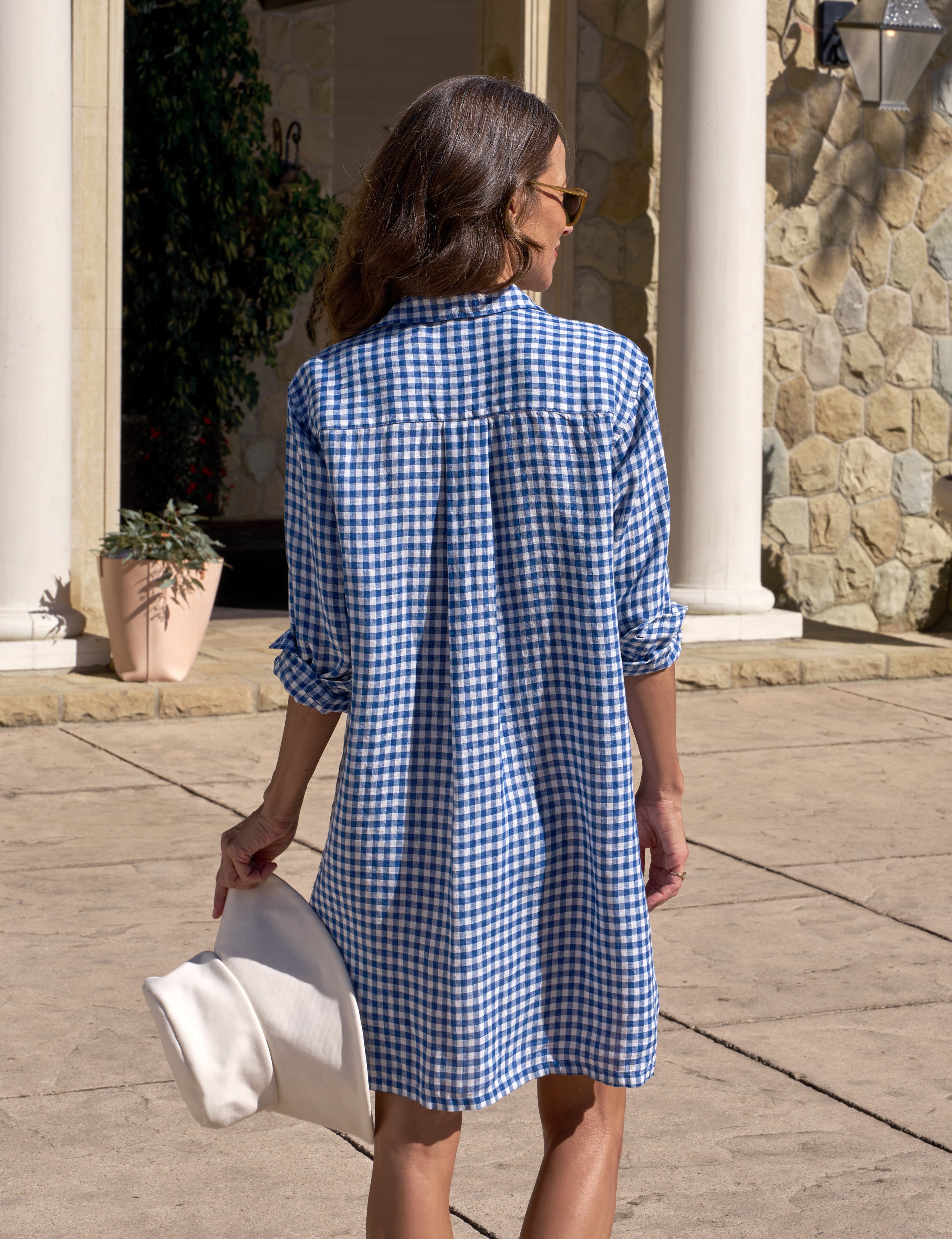 Woman wearing a blue checkered dress walking outdoors.