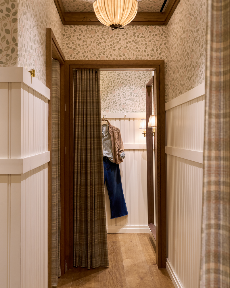 Passage into a room with patterned wallpaper and wooden flooring.