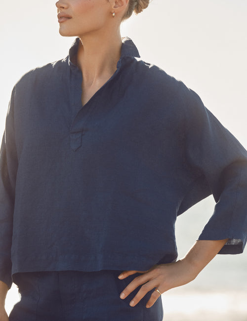 Person wearing a navy blue shirt with a blurred background, view 3