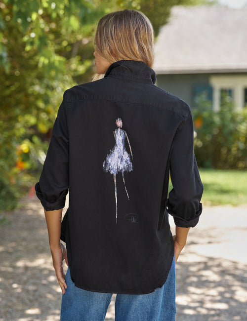 Person wearing a black shirt with a white graphic on the back, standing outdoors., front view