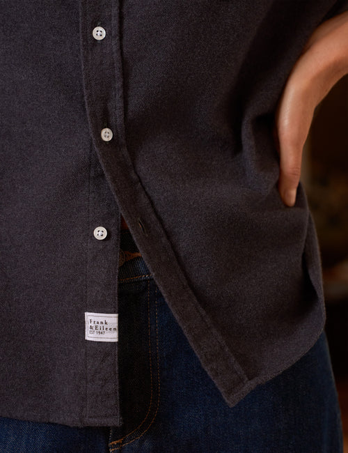 Close-up of a dark charcoal gray button-down shirt worn with blue jeans, showing the fabric texture, a side pocket, and a white 'Frank & Eileen' brand label., view 3