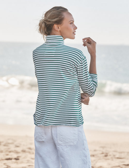 Woman wearing a striped shirt and white pants on a beach, alternate view