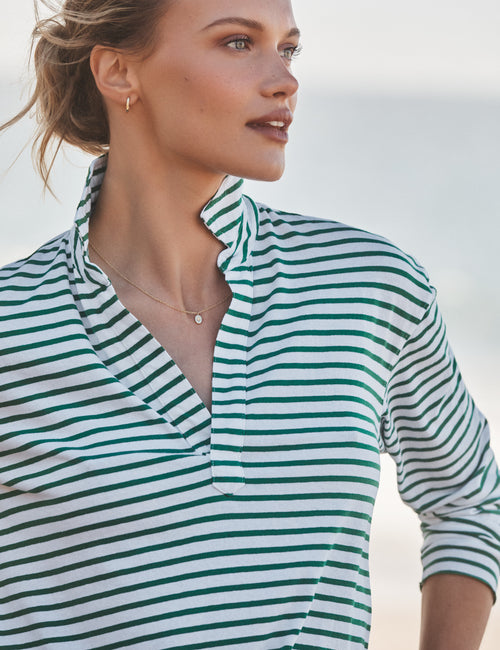 Woman wearing a green and white striped shirt against a blurred natural background, view 3