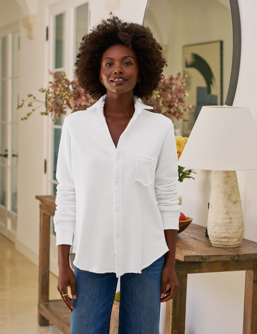 Woman wearing a white shirt and blue jeans standing in a room with decor elements., front view