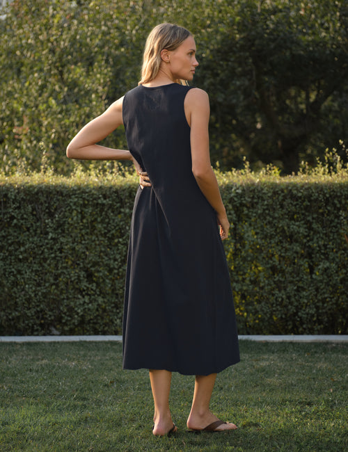 Woman in a navy dress standing in a garden, alternate view