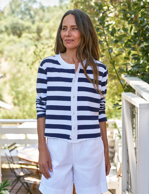 Woman wearing a navy and white striped shirt with white shorts outdoors., front view