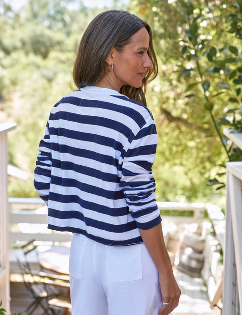 Woman wearing a blue and white striped shirt outdoors with greenery in the background, alternate view