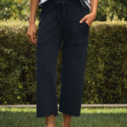 Person wearing navy pants and a striped shirt standing on grass with a hedge in the background