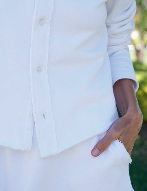 Person wearing a white button-up shirt with a blurred background, view 3