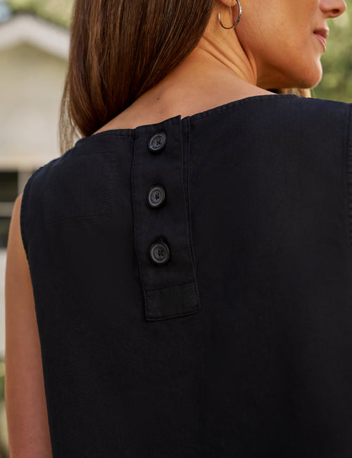 Black sleeveless top with button details on a blurred background, view 3