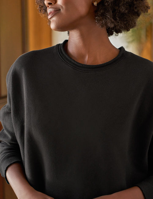 Person wearing a black sweater with a blurred background, view 3