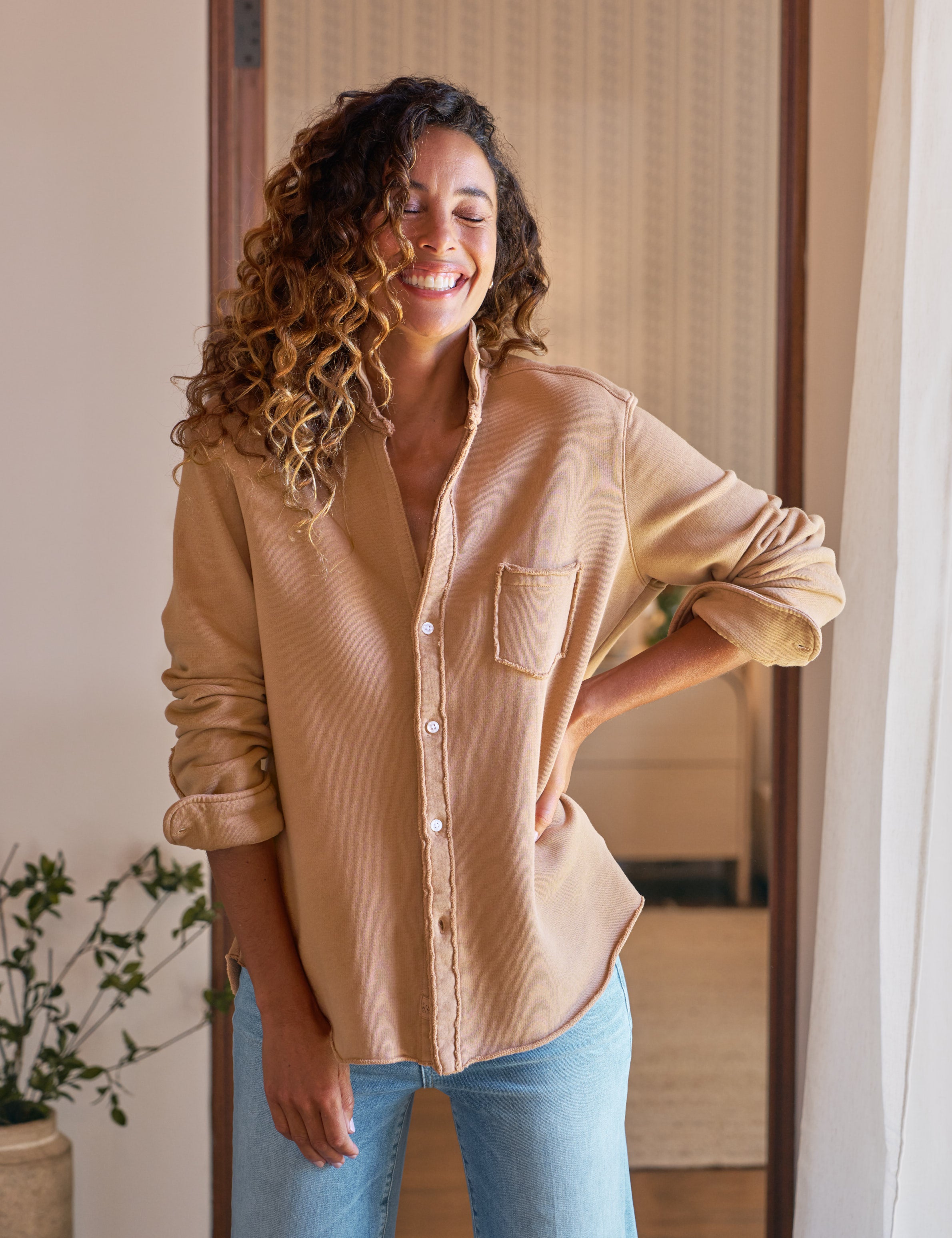 Woman wearing a beige shirt and blue jeans indoors