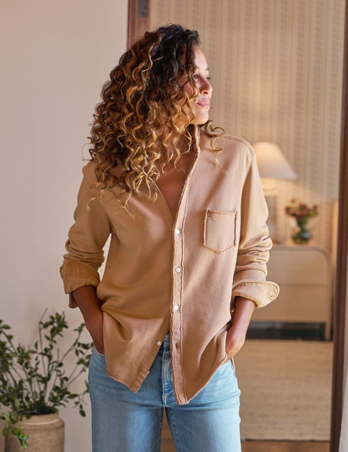 Woman wearing a beige shirt and blue jeans indoors, view 4