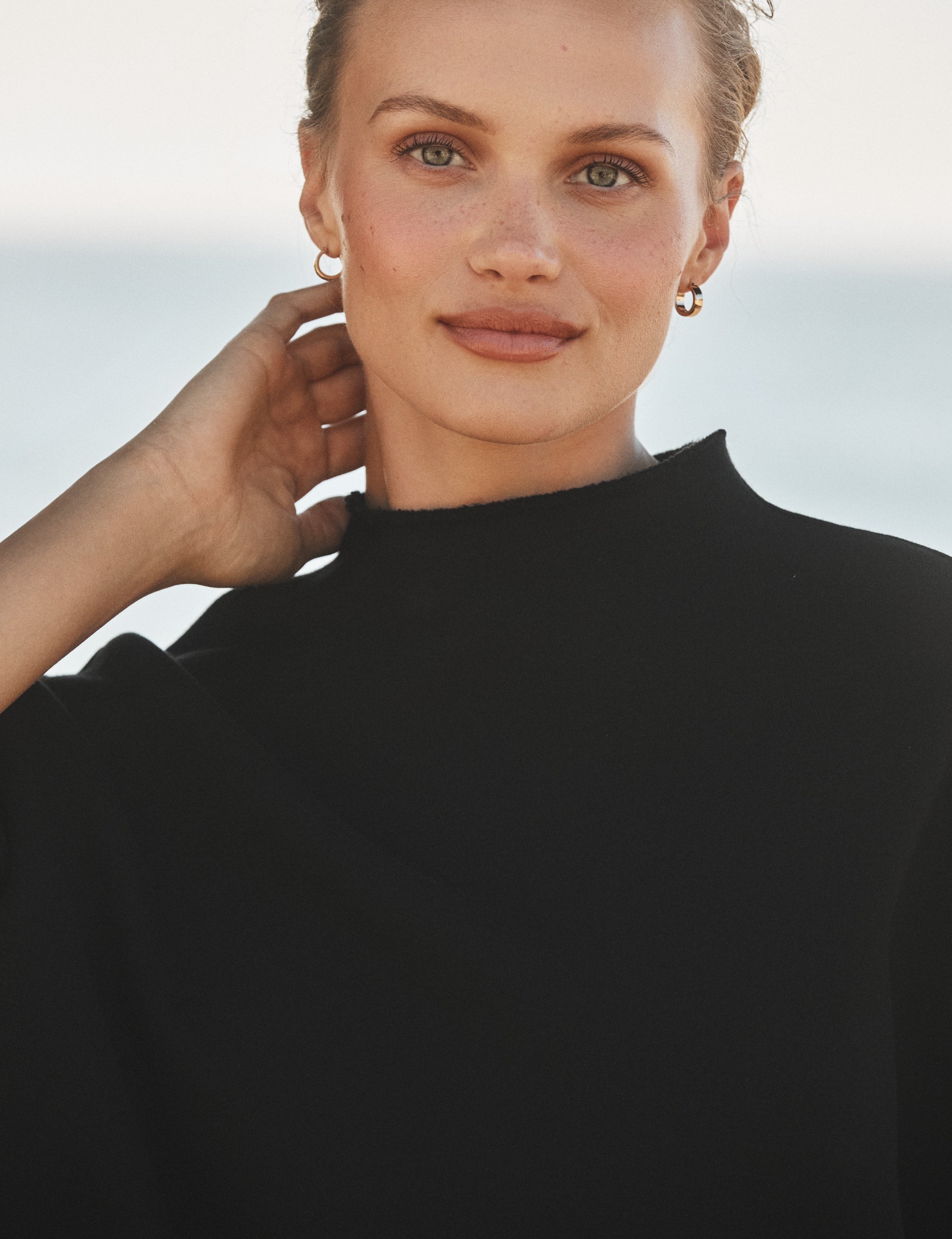 Woman wearing a black sweater against a light background, view 3