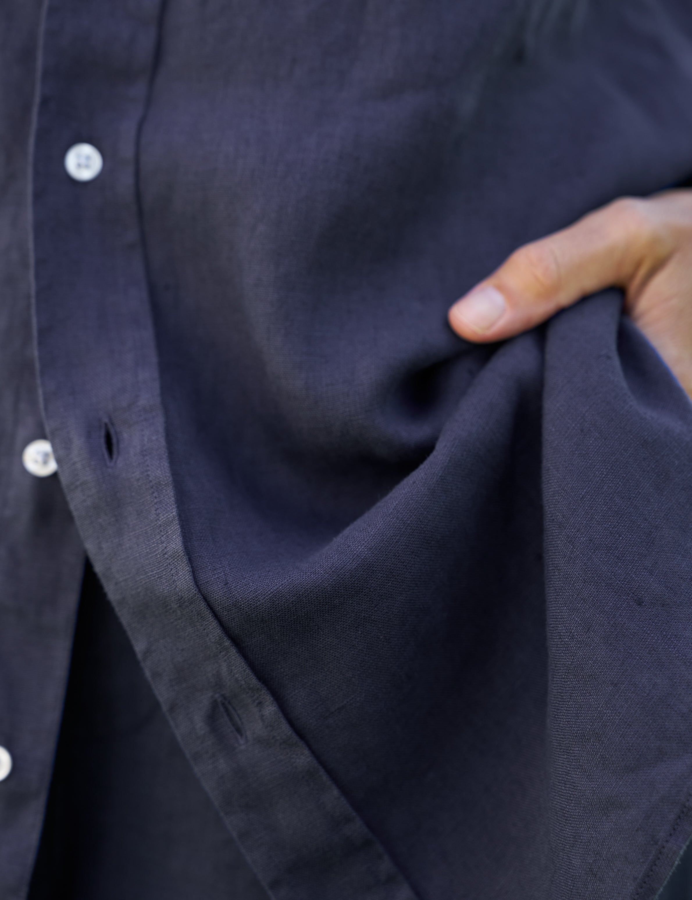 Close-up of a person holding a dark blue fabric with buttons.