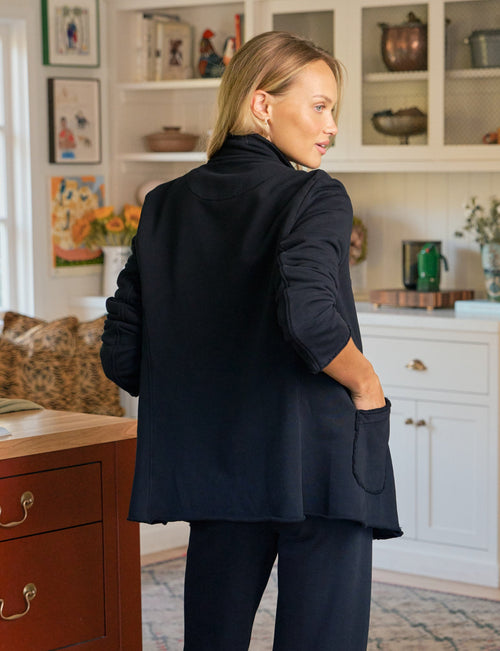 Woman in a navy set standing in a kitchen., alternate view