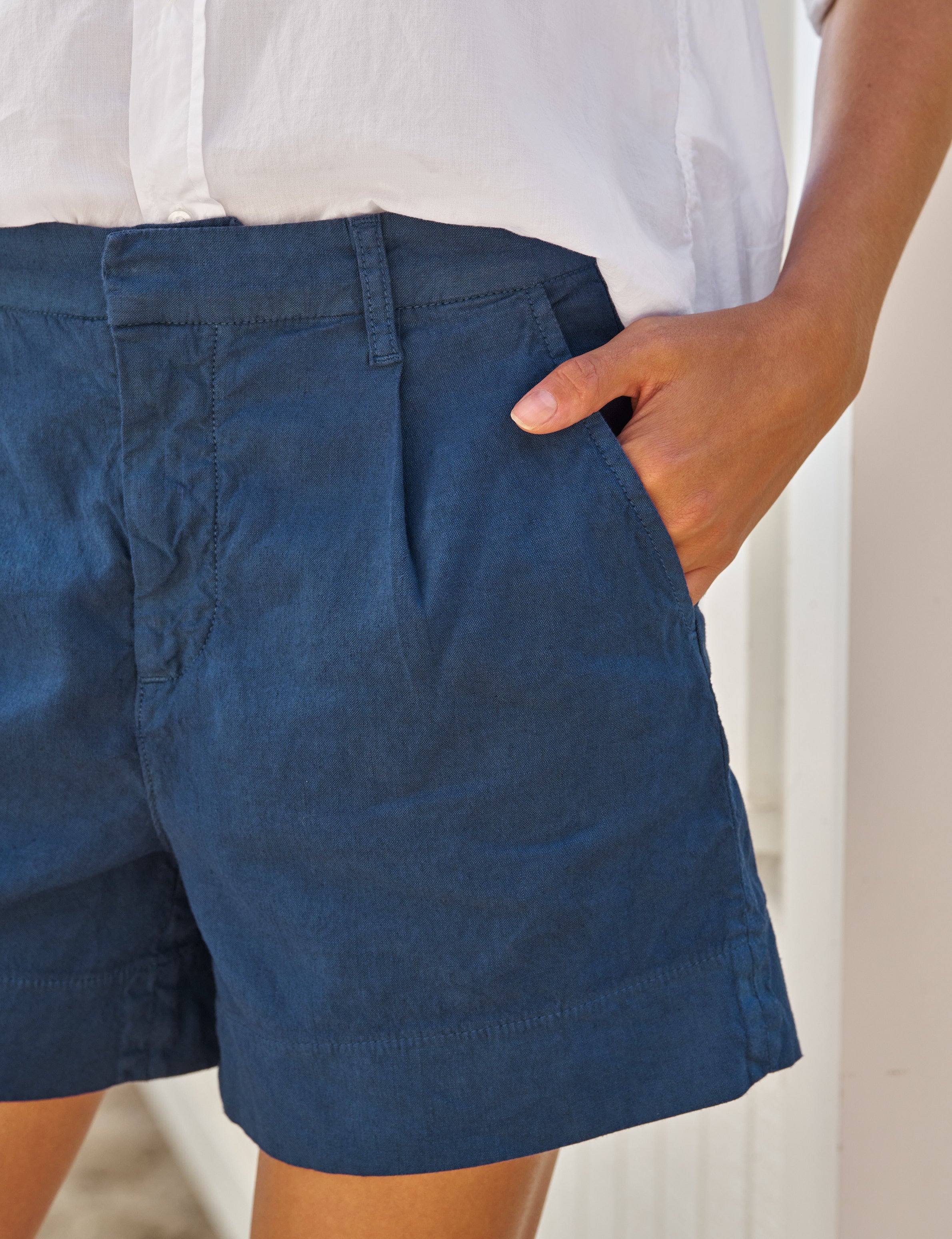 Person wearing blue shorts with a neutral background, alternate view
