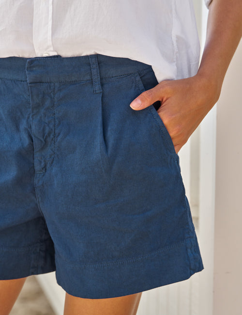 Person wearing blue shorts with a neutral background, alternate view