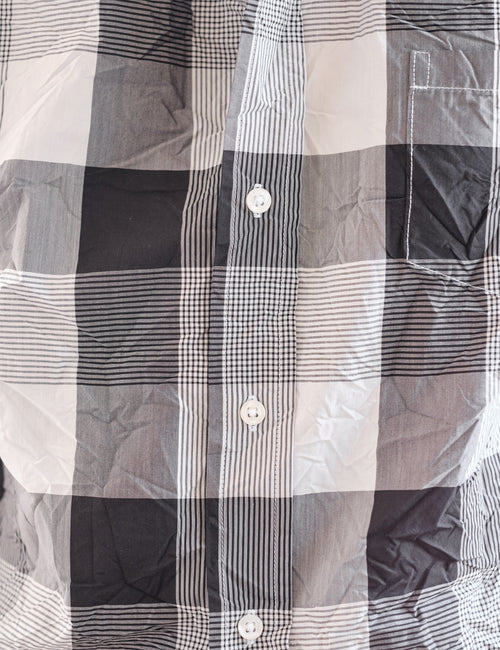 A close-up of a plaid button-up shirt in black, white, and gray, showing the fabric texture and pattern details., view 3