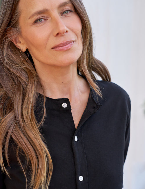 Woman wearing a black button-up shirt against a white background, view 3