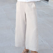 Woman in white shirt and beige pants standing in front of a classical building.