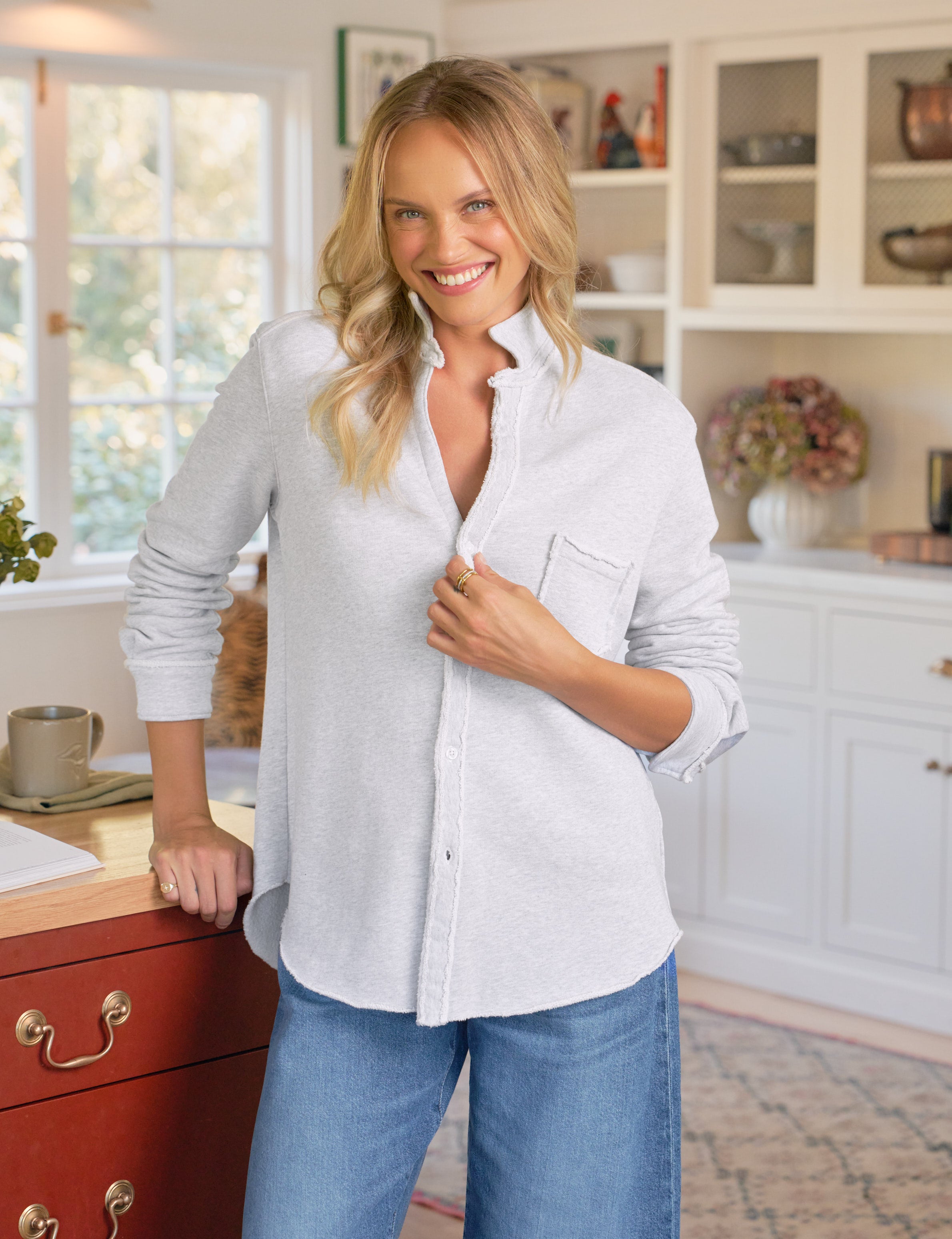 Woman wearing a gray shirt and blue jeans standing in a kitchen.