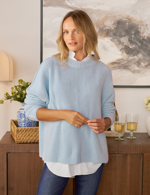 Woman wearing a light blue sweater in a home setting, front view