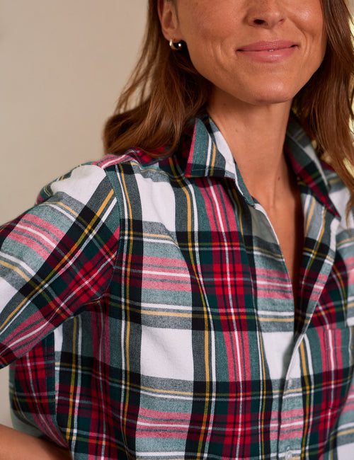 A close-up of a woman wearing a short-sleeve plaid button-up shirt. The shirt features a tartan pattern of red, green, white, yellow, and blue stripes., view 3