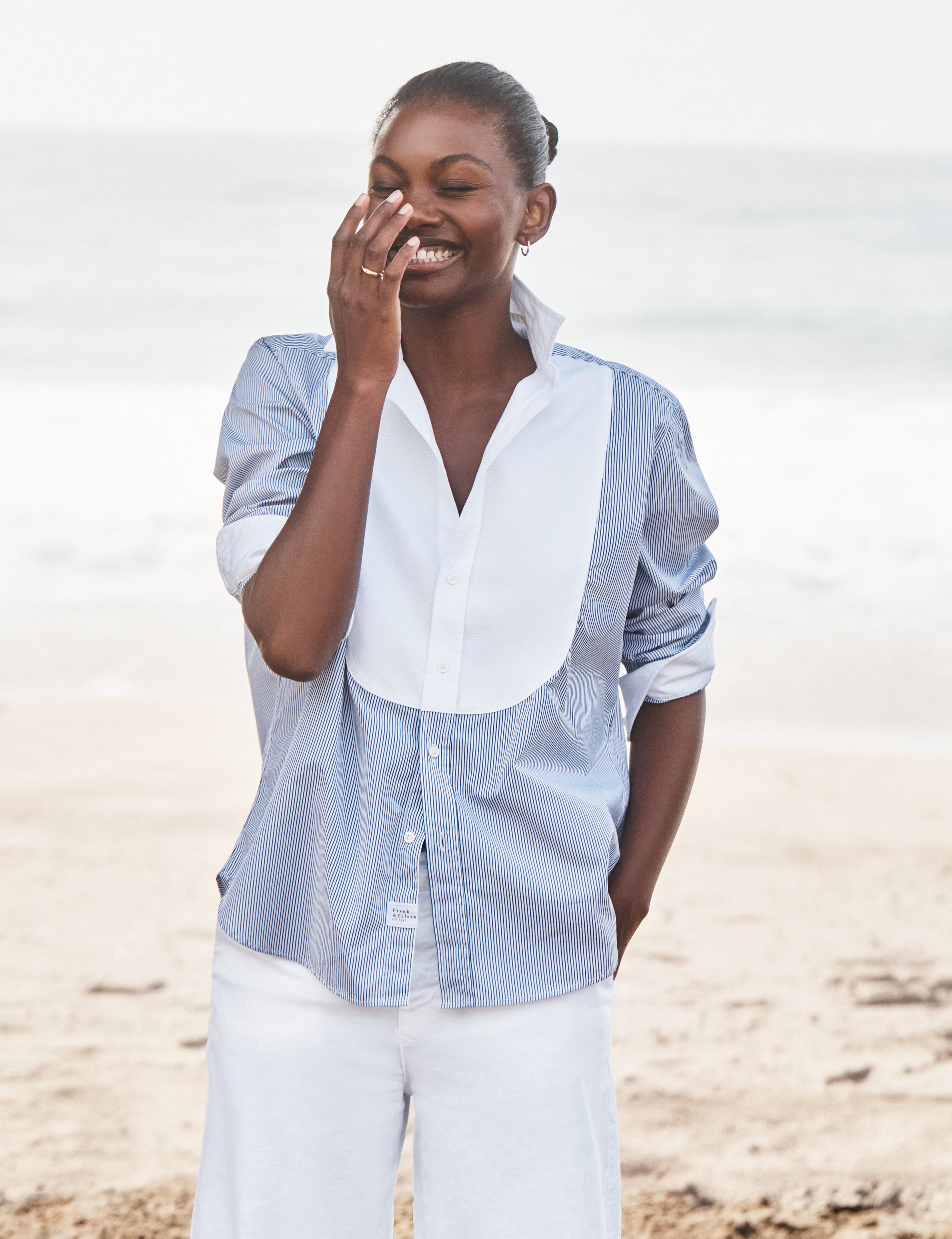 Woman wearing a light blue and white striped shirt on a beach, front view