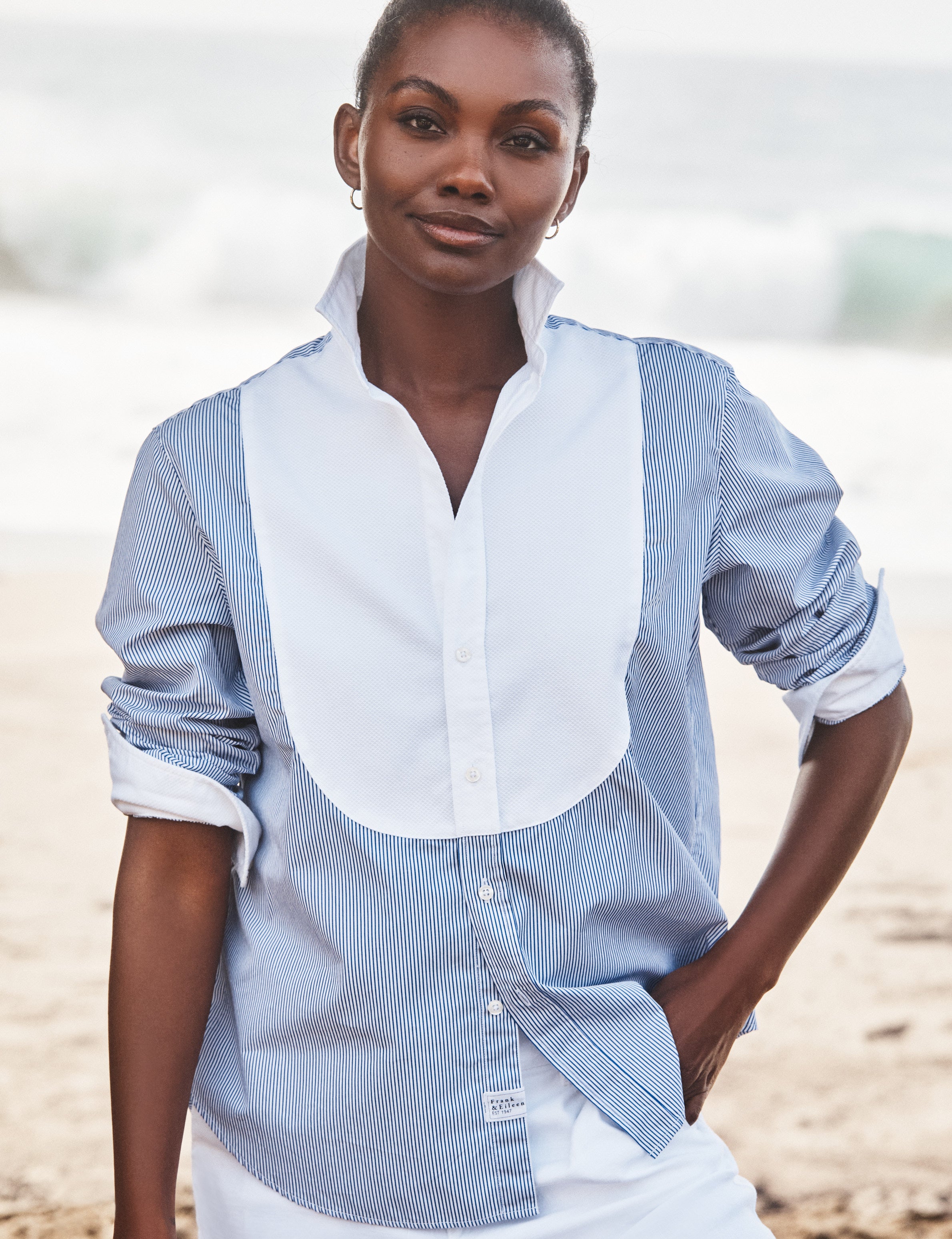 Woman wearing a blue and white striped shirt on a beach, view 3