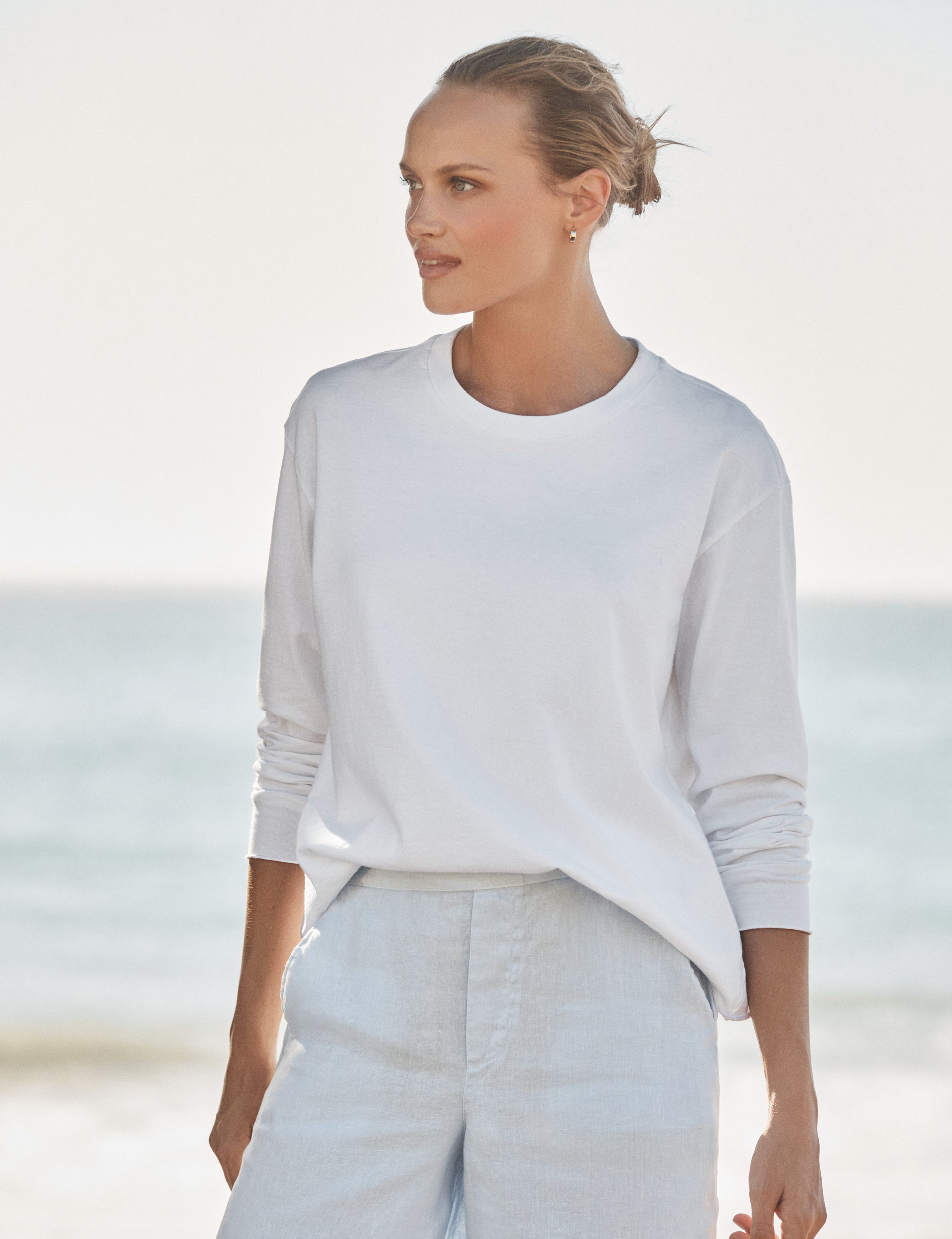 Woman wearing a white shirt and pants on a beach., front view