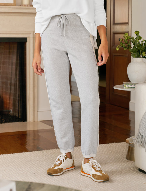 Person wearing gray sweatpants and brown sneakers in a living room setting, front view