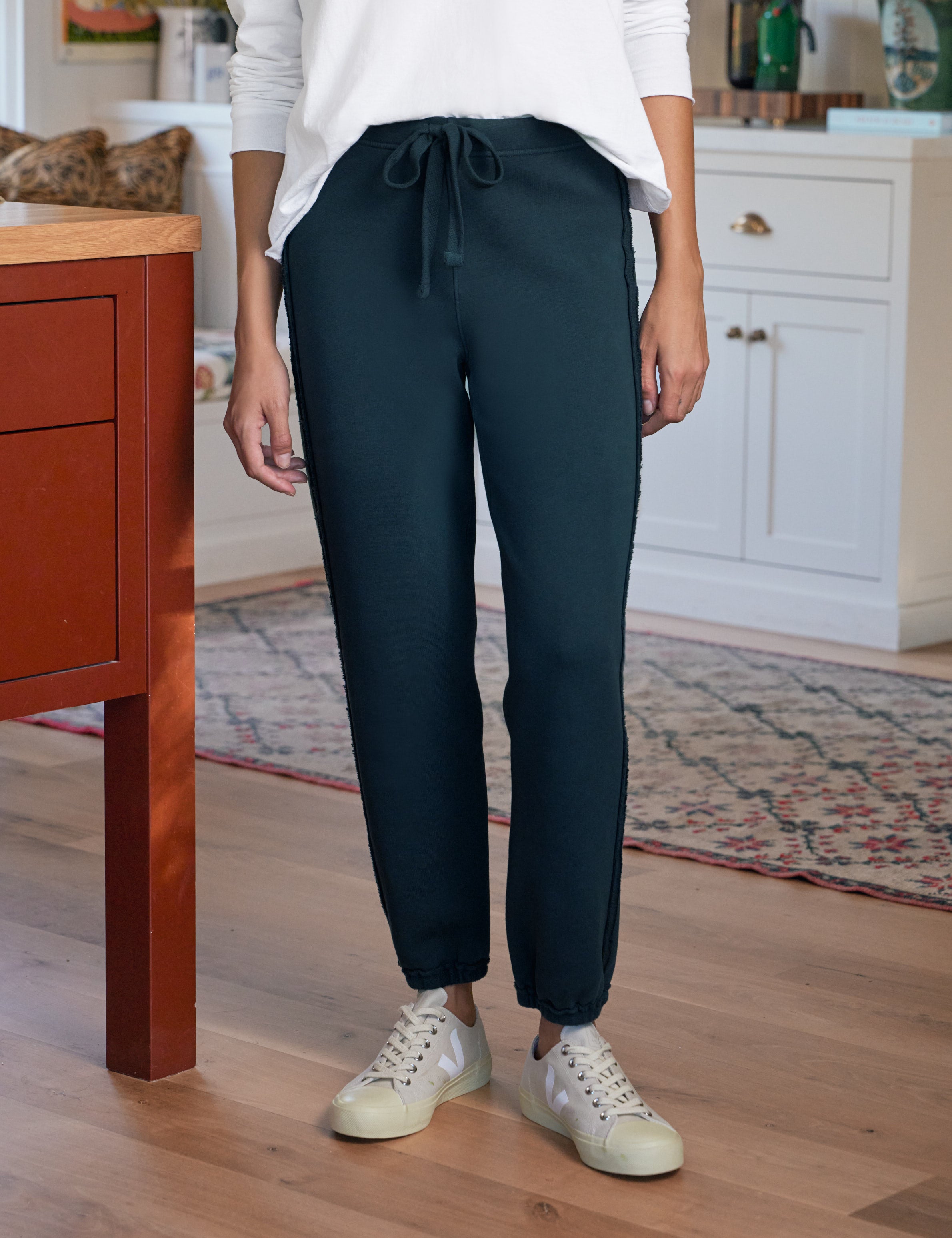 Person wearing navy jogger pants and white sneakers in a home setting
