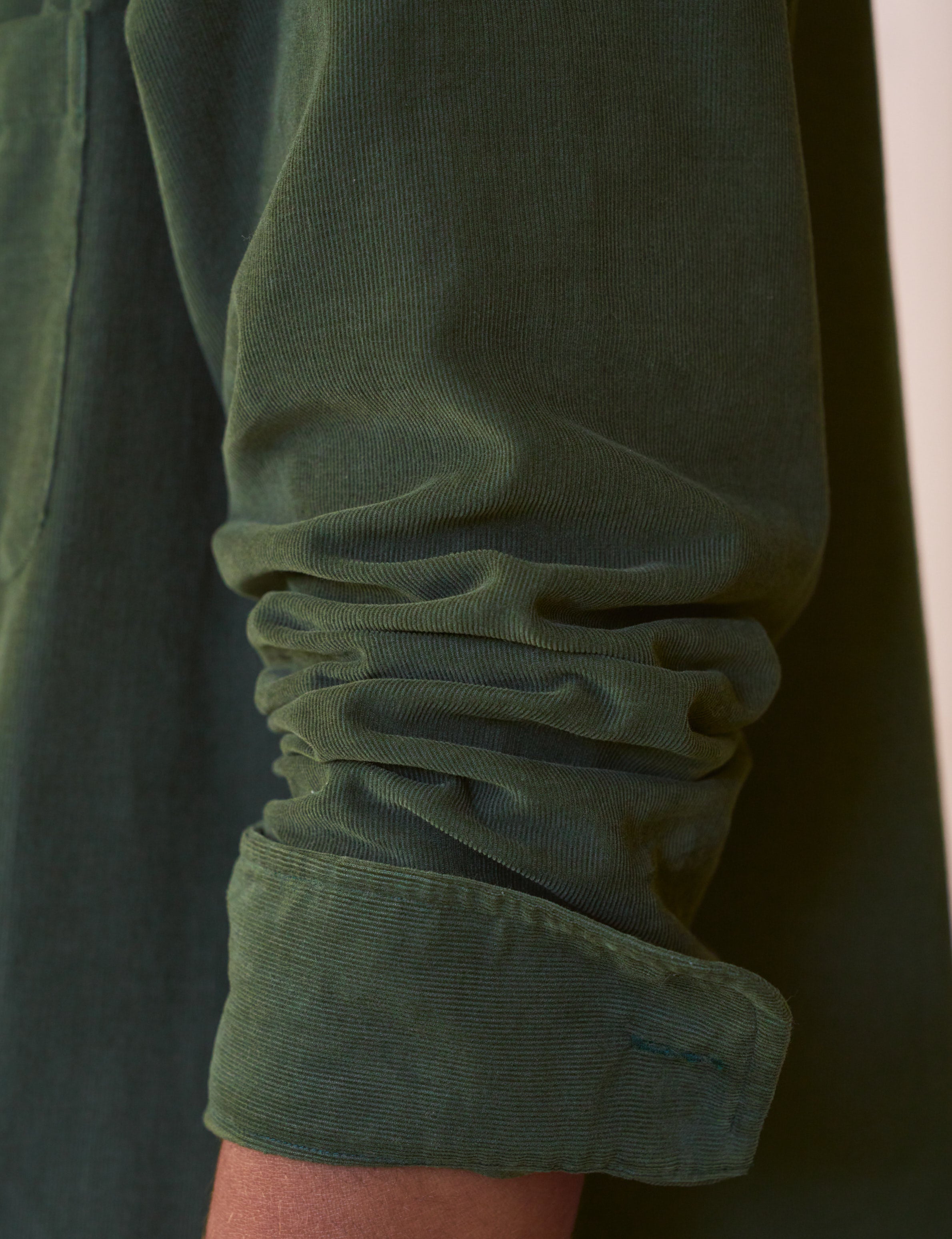 Close-up of a green sleeve with rolled-up cuff on a dark background