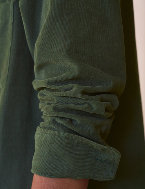 Close-up of a green sleeve with rolled-up cuff on a dark background, view 5