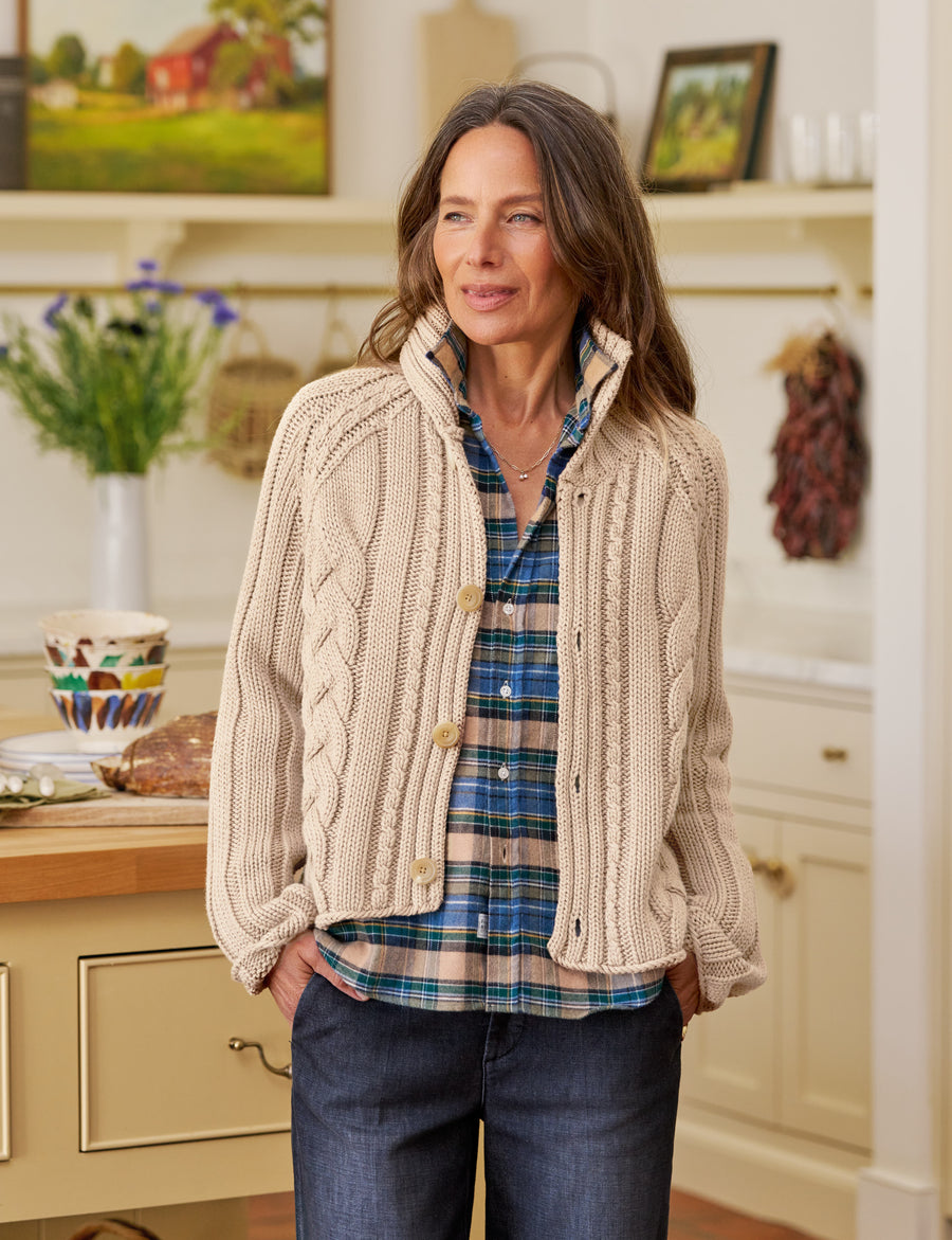 Woman wearing a beige cable knit cardigan in a kitchen setting