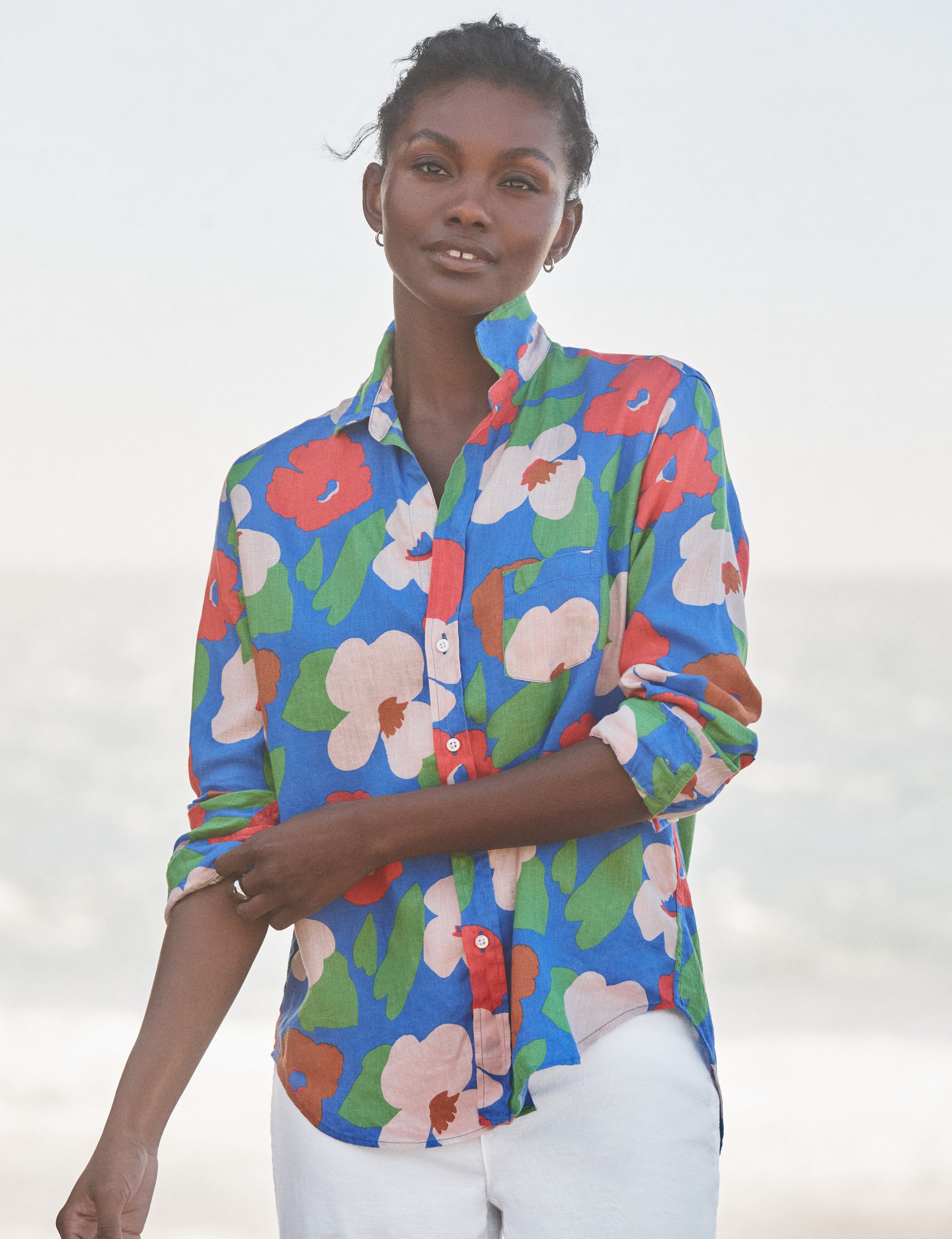 Woman wearing a colorful floral shirt against a white background, front view
