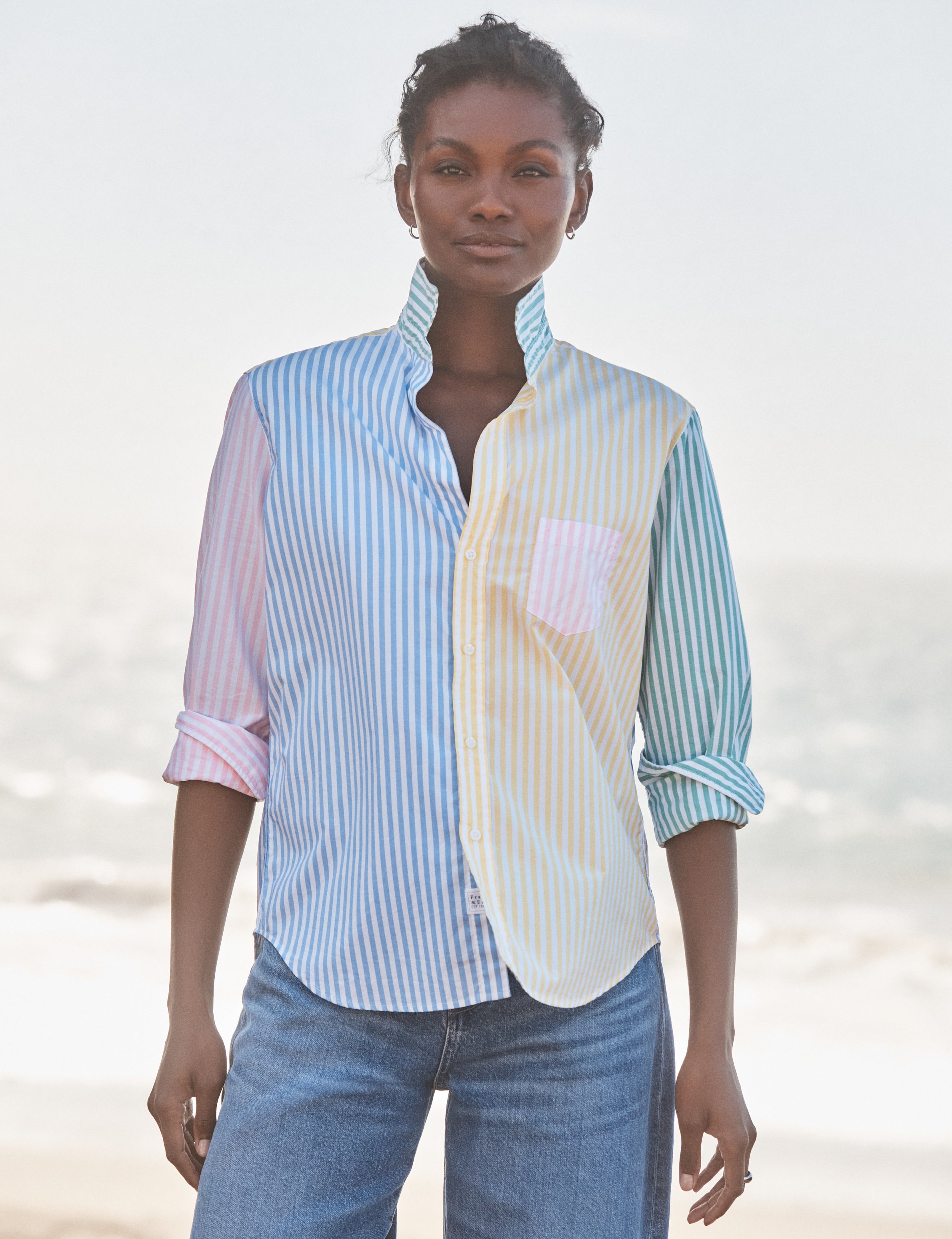 Woman wearing a two-tone shirt with a blurred beach background, front view