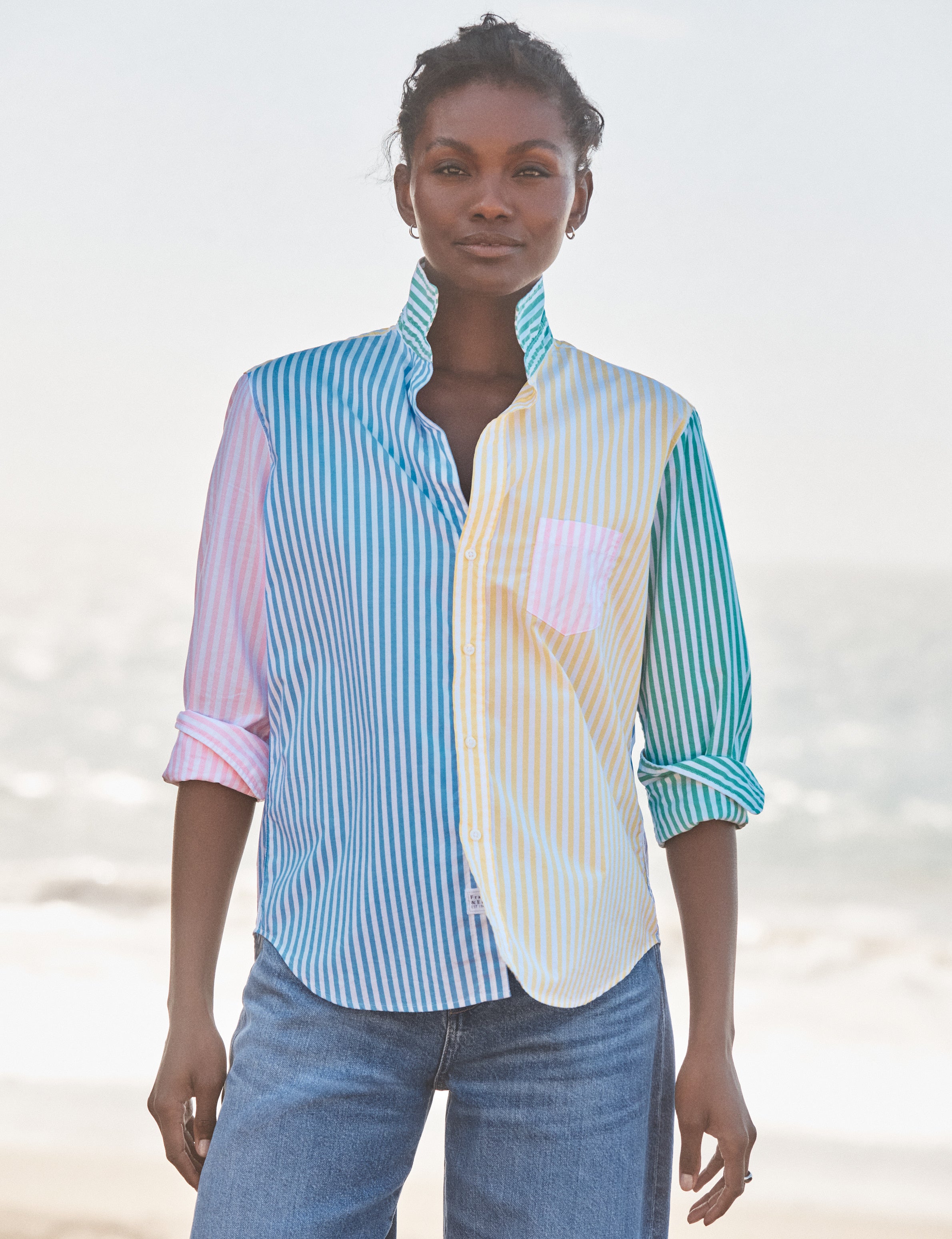 Woman wearing a colorful striped shirt with a blurred beach background, front view